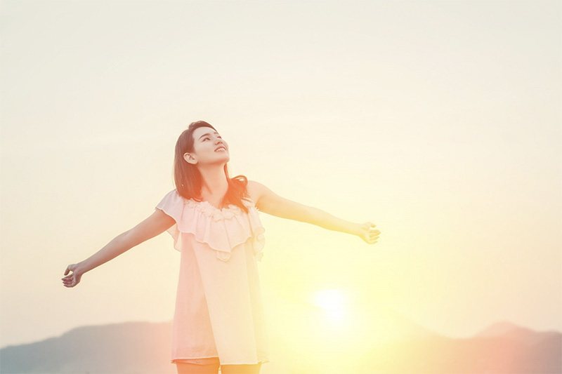 朝日に向かって両手を広げる女性